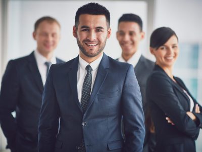 Portrait of confident business partners looking at camera with smiling leader in front
